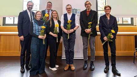 Mehrere Personen stehen nebeneinander, einige mit Blumen in den Händen.