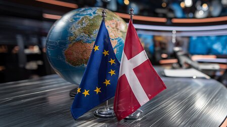 Zwei Tischflaggen stehen vor einem Globus.