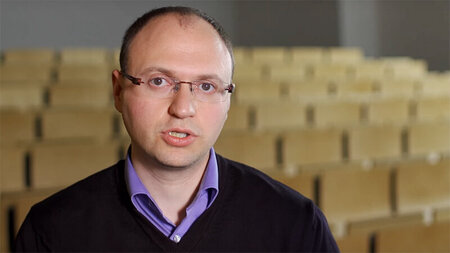 Ein Mann steht vor einem leeren Hörsaal.