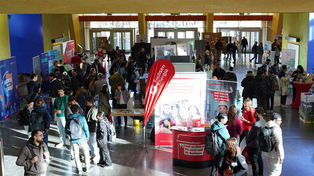 Mehrer Personen stehen in einem Foyer an Messeständen.