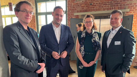 Drei Männer und eine Frau stehen nebeneinander.