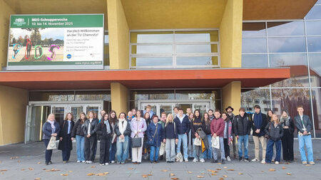 Gruppe an Schülerinnen und Schülern steht vor einem Gebäude