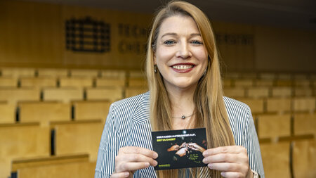 Eine junge Frau hält zwei Postkarten hoch.