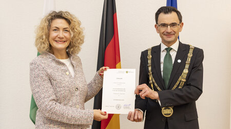 Ein Mann überreicht eine Urkunde an eine Frau.