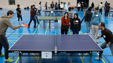 Mehrere Personen spielen Tischtennis.