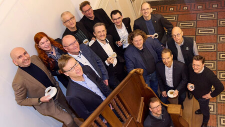 Mehrere Personen stehen auf einer Treppe im Foyer eines Hauses.