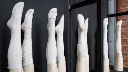 In einem Regal stehen Beine von Schaufensterpuppen, die mit weißen Strümpfen, die Laufmaschen enthalten, überzogen wurden.