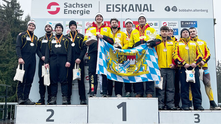 Sportler stehen mit Medaillen auf einem Podest zur Siegerehrung