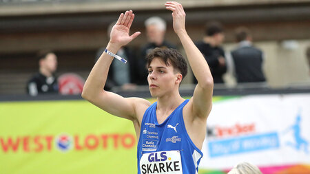 Ein Mann im Sport-Shirt hebt beide Arme nach oben.