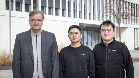 Drei Männer stehen vor einem Gebäude