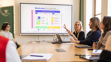 Menschen sitzen in einer Gesprächsrunde an einem Tisch zusammen