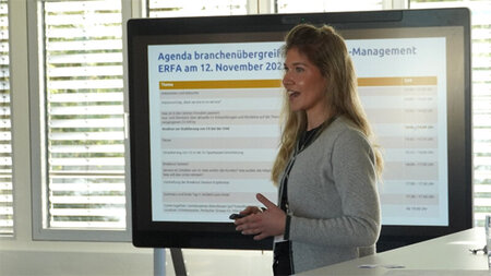 Eine Frau steht vor einem Monitor.