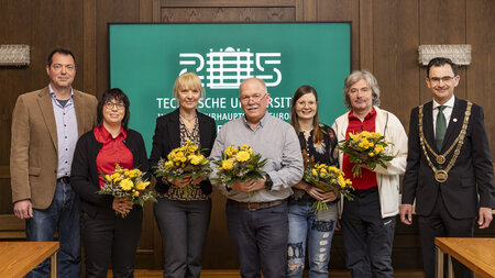 Mehrere Personen mit Blumensträußen in der Hand stehen nebeneinander.