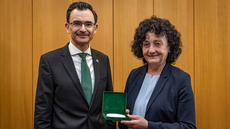 A man hands a white medal to a woman.