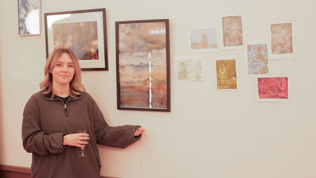 Frau steht für einer Wand mit ausgestellten Bildern