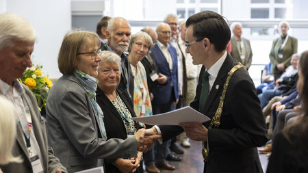 Mehrere Personen stehen an einer Straßenkreuzung vor einem Gebäude.