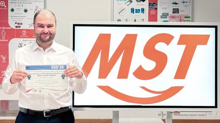 Ein Mann hält eine Urkunde in den Händen.