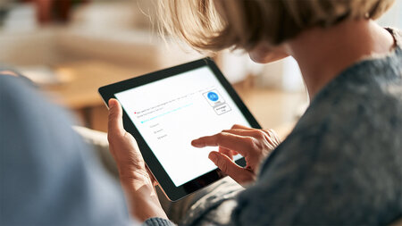 Eine Frau berührt mit dem Finger den Bildschirm eines Tabletts.