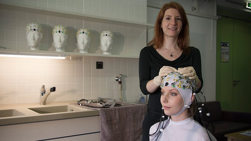 Prof. Alexandra Bendixen demonstriert Vorbereitung des EEG an sitzender Person