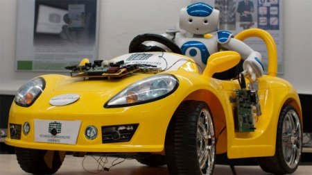 Robot sits in a yellow car.