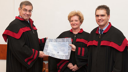 A man gets a certificate from two other persons.