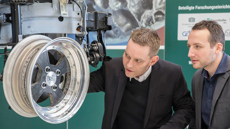 Two men inspect a lightweight wheel