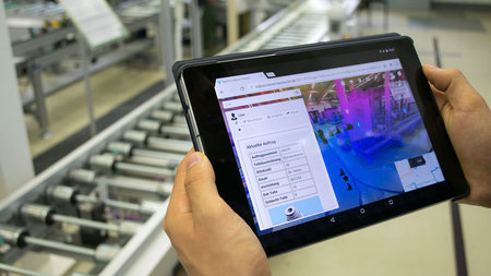 Person hält ein Tablet in der Hand, mit welchem die Produktion digitalisiert werden kann