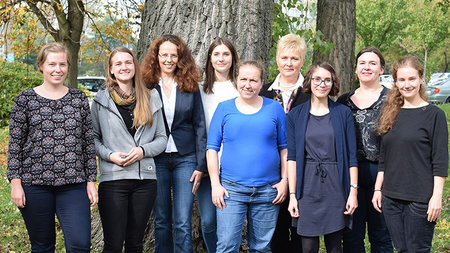 Eine Gruppe mehrerer Frauen steht vor einem Baum