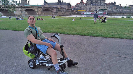 A young man is sitting in a electric scooter