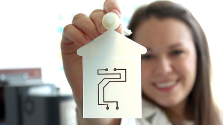 Frau h�lt Papier mit gedruckter Elektronik in die Kamera.