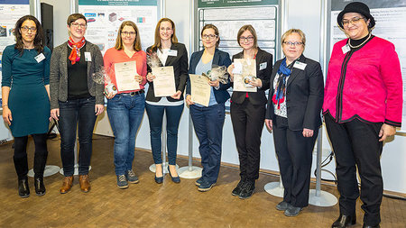 8 Frauen verschiedenen Alters. 4 von ihnen halten Urkunden. 