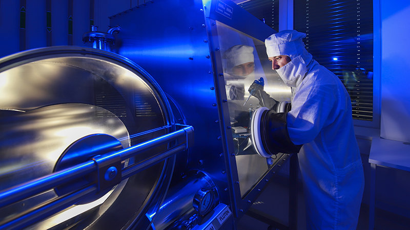 A researcher works using a glovebox. 