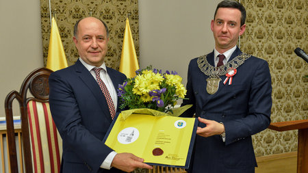 Two man holding a certificate. 