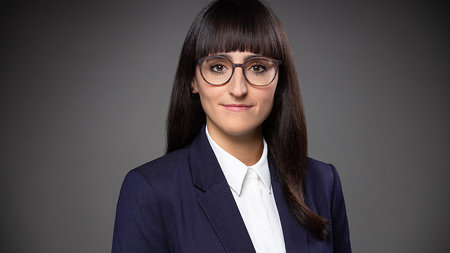 Young woman with long hair and glasses.