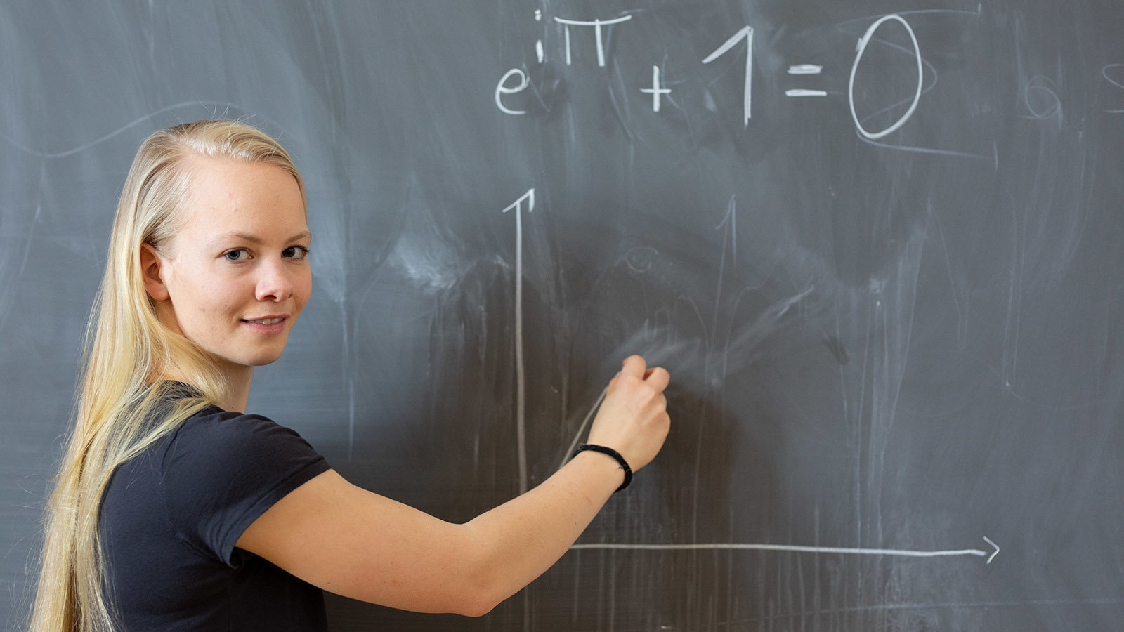 Junge Frau schreibt Formeln an eine Tafel.