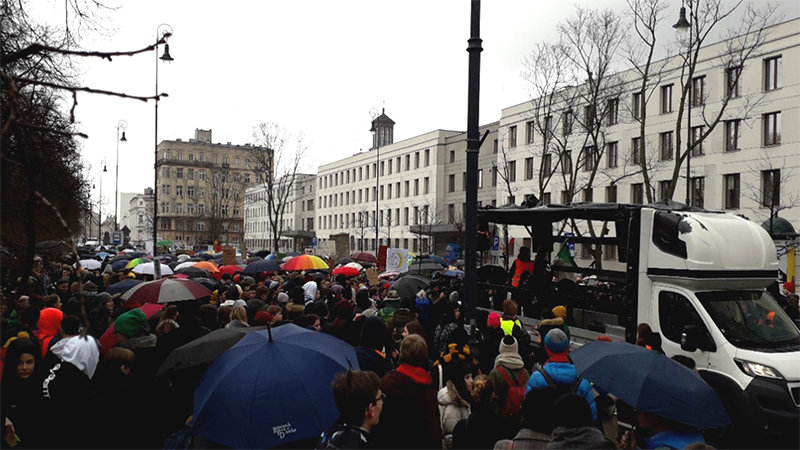 Demonstranten stehen mit Regenschirmen auf einer Straße