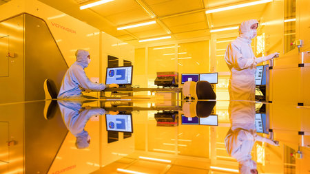 Two men in protective suits work in a lab.