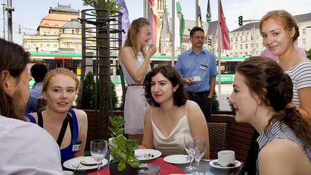 5 young woman talking to each other. The Chemnitz Opera house is in the background.