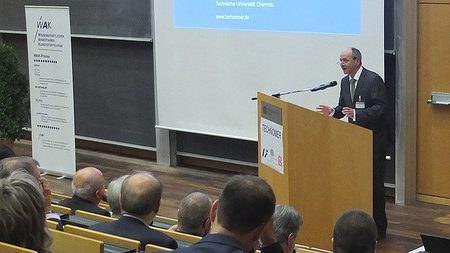 Mann steht am Rednerpult und spricht zu Personen, die im H�rsaal sitzen