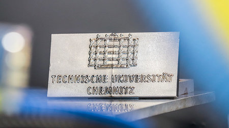 Metallteil mit Logo der TU Chemnitz
