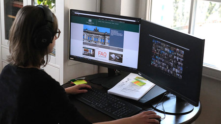 A woman uses a desktop computer with two screens.