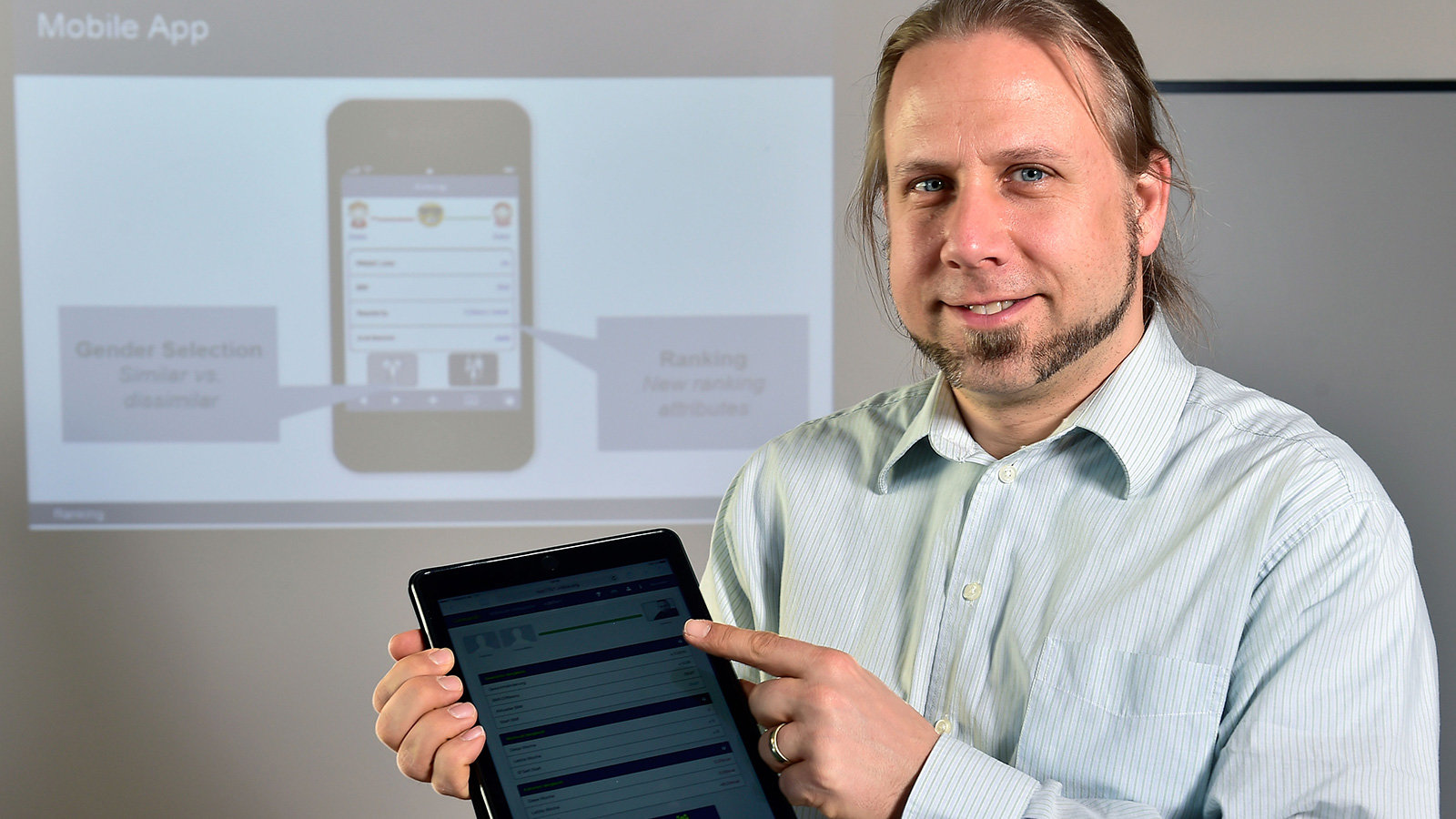 Mann hält schwarzes Tablet in der Hand.