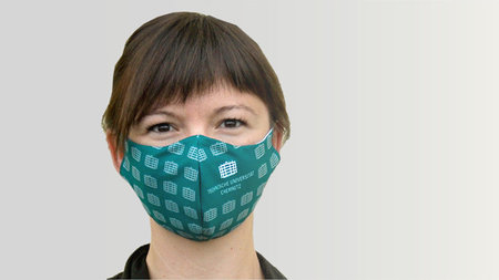 A woman wears a Chemnitz University of Technology branded face mask.