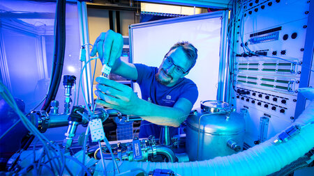 A man in a t-shirt and glasses works in a laboratory.