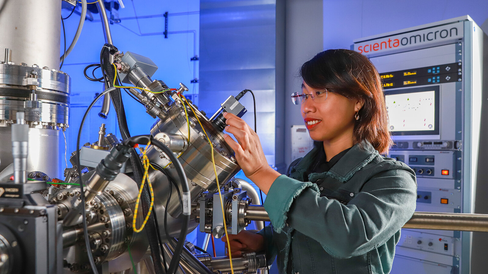 A smiling woman uses a microscope.