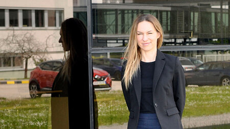 Porträt einer Frau, die vor einer Fensterfront steht.