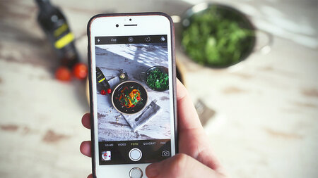 Image of a cell phone taking a photo of a skillet filled with food