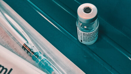 Eine Impfampulle liegt neben einer Spritze.