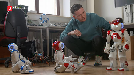 Ein junger Mann tätschelt einen kleinen Roboter.