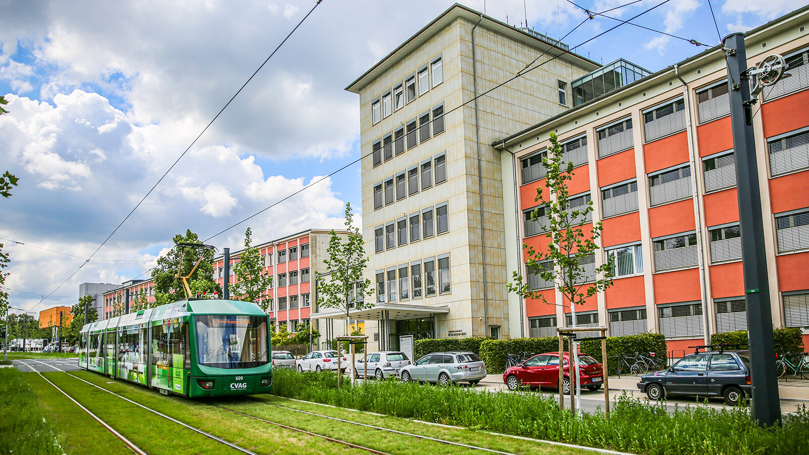 Eine Straßenbahn fährt vor einer Gebäudefront entlang.